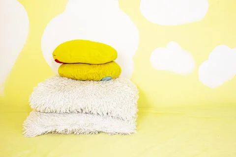 Decorative pillows on a yellow wall with clouds in the children's room Stock Photos