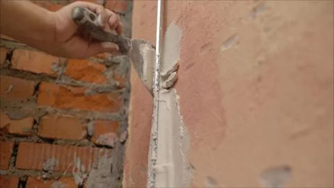 Decorative plaster coating. Man does ragged texture on the wall using a spatu Stock Photos
