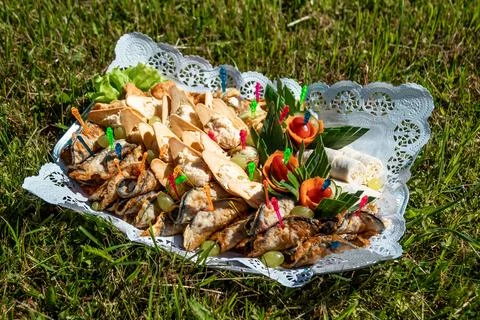 Decorative Platter with Grilled Fish, Bread, and Vegetables on Grass Stock Photos