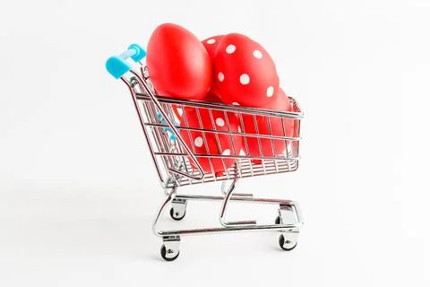 Decorative red Easter eggs in a small supermarket shopping cart isolated Stock Photos