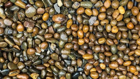 Decorative river pebbles on a drainage grate. Textured background Фото