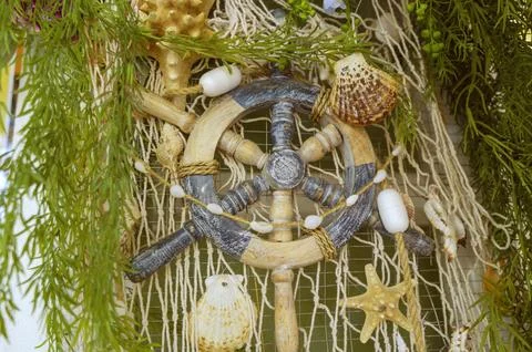 Decorative ship steering wheel with shells and a fishing net. Stock Photos
