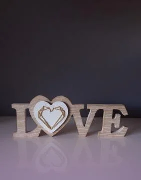 Decorative sign with the letters LOVE in wood in a dark background with pink Stock Photos