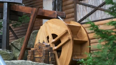 A decorative small watermill in the backyard spins under the spray of water. Stock Footage 165792915