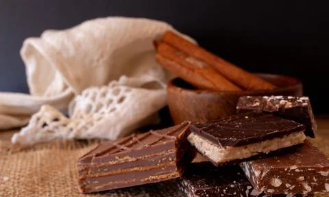 Decorative stack of different flavoured chocolates in a rustic kitchen. Stock Photos