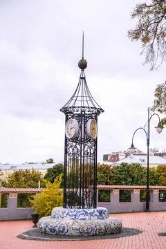 Decorative street clock tower with multiple faces set on a mosaic base in an Stock Photos