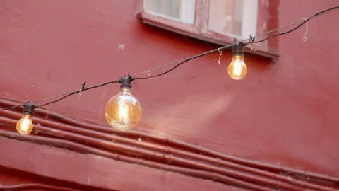 Decorative string light bulbs hanging on a red building wall Stock Footage 324719826