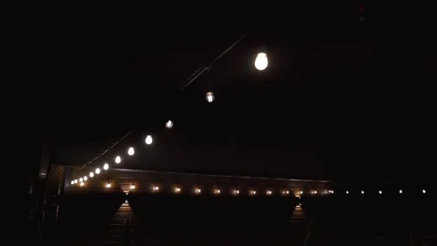 Decorative string light bulbs swaying at night Stock Footage 342344754