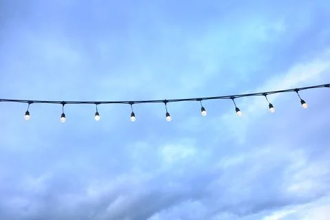 Decorative string light hanging outdoors under a clear daylight sky Stock Photos