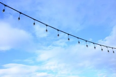 Decorative string light hanging outdoors under a clear daylight sky Stock Photos