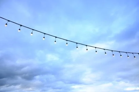Decorative string light hanging outdoors under a clear daylight sky Stock Photos