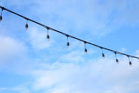 Decorative string light hanging outdoors under a clear daylight sky Stock Photos
