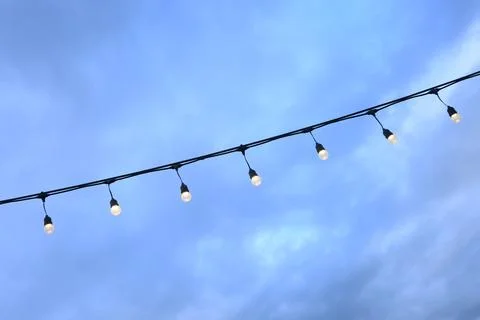 Decorative string light hanging outdoors under a clear daylight sky Stock Photos