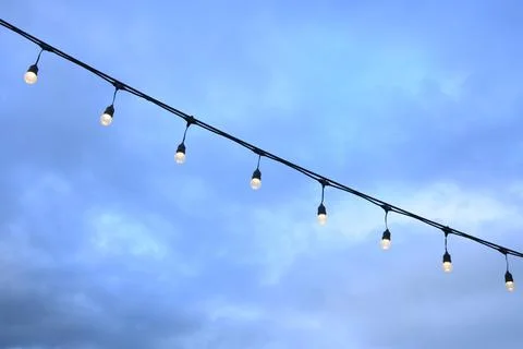 Decorative string light hanging outdoors under a clear daylight sky Stock Photos