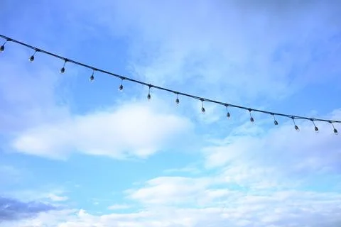 Decorative string light hanging outdoors under a clear daylight sky Stock Photos