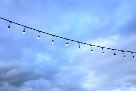 Decorative string light hanging outdoors under a clear daylight sky Stock Photos