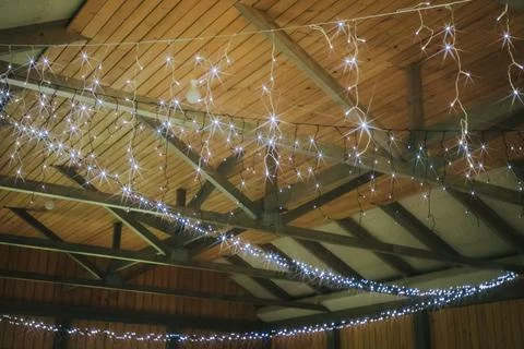 Decorative string lights hanging from wooden beams in a rustic interior spa.. Stock Photos
