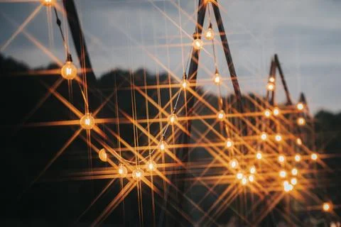 Decorative string lights illuminated at dusk, creating a warm ambiance with.. Stock Photos