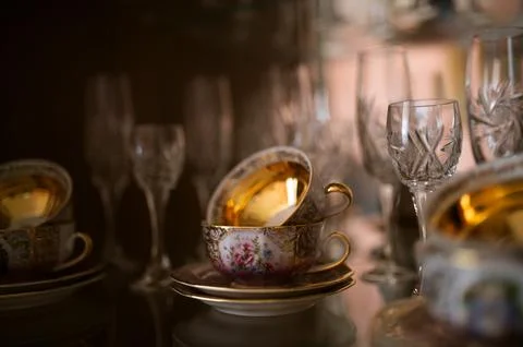 Decorative teacups and crystal stemware in a glass cabinet Stock Photos