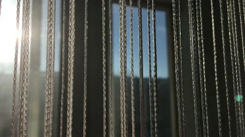 Decorative thread curtains on a window on a sunny day, close up Stock Footage 147851362