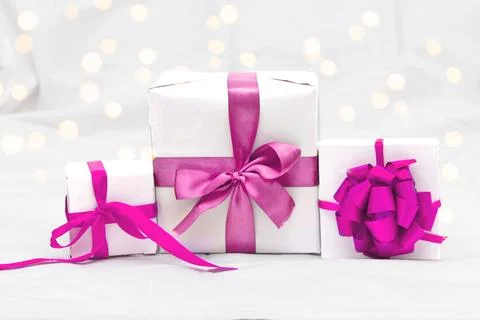 Decorative three white gift box with a large barbie pink bow against a back.. Stock Photos
