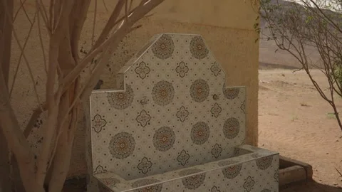 Decorative tiled fountain bench under tree in Morocco desert 库存影片 337432830