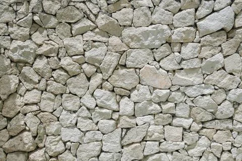 Decorative uneven cracked pattern of real stone wall surface with light pas.. Stock Photos