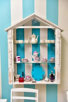 Decorative wall shelf with tea set in salon interior Stock Photos