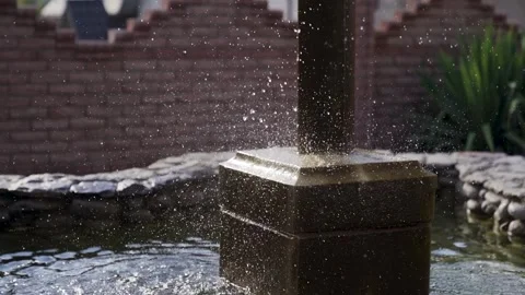 Decorative waterfall on natural stones with eagle statue fnd blue sky. Slowmo Stock Footage 221017405