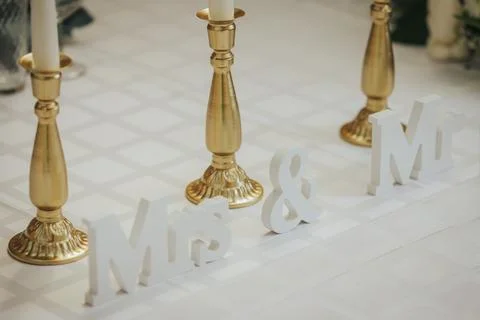 Decorative wedding table setting featuring gold candlesticks and white wood.. Stock Photos