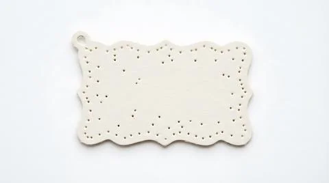 Decorative white ceramic gift tag with scalloped edges and perforated borde.. Stock Photos