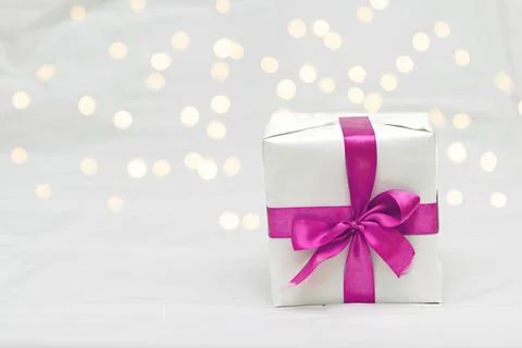 Decorative white gift box with a large barbie pink bow against a background.. Stock Photos