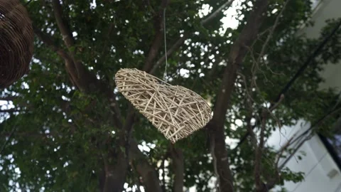 Decorative wicker heart hanging from a tree on a street Stock Footage 157647453