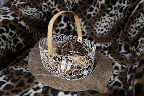 Decorative wire basket with abstract objects stands on an armchair. 스톡 사진