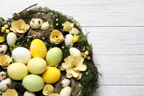 Decorative wreath with Easter eggs on white wooden background, top view Stock Photos