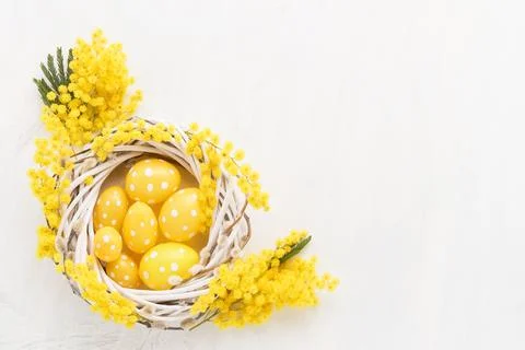 Decorative yellow Easter eggs and mimosa wreath on a white background. Flat lay Stock-Fotos