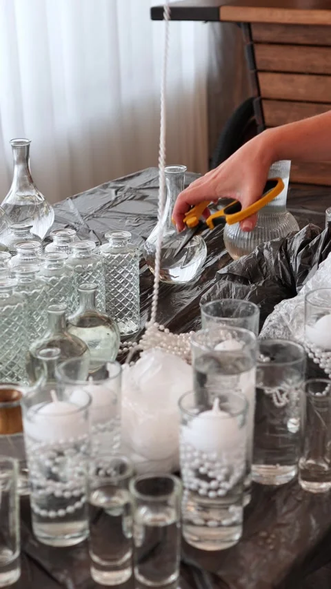 Decorator cuts a necklace for wedding table decoration. vases, candles with a ne Stock Footage 318932402
