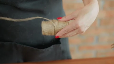 Decorator holding spool of twine while pulling coarse string Stock Footage 320333819
