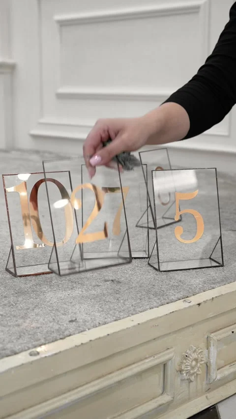 A decorator is preparing table number plates for a celebration in a banquet hall Stock Footage 318922258