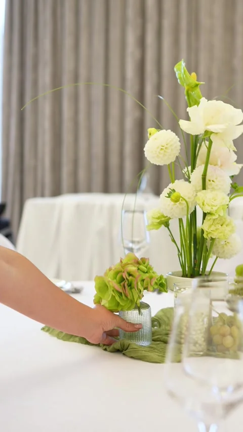 Decorator puts hydrangea in a vase on the wedding table. wedding flower arrangem Stock Footage 318932256