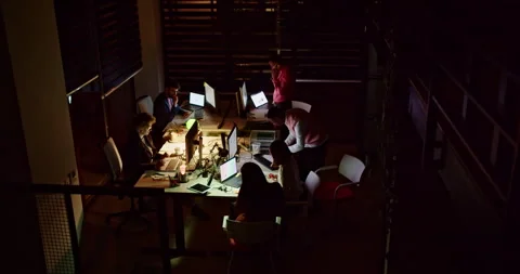 Dedicated businesspeople engaged in collaborative work in a dimly lit office Stock Footage 264955514