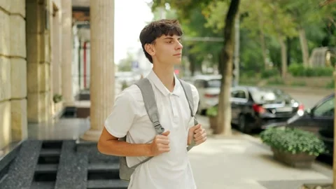Dedicated caucasian learner wearing a backpack standing near the college Stock-Footage 345968696