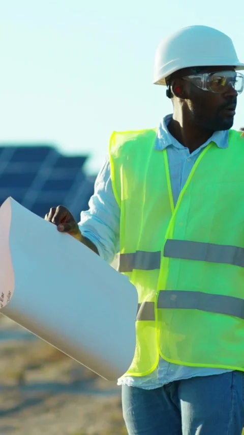 A dedicated construction worker thoroughly reviewing detailed plans at a solar Vídeo Stock 314206242