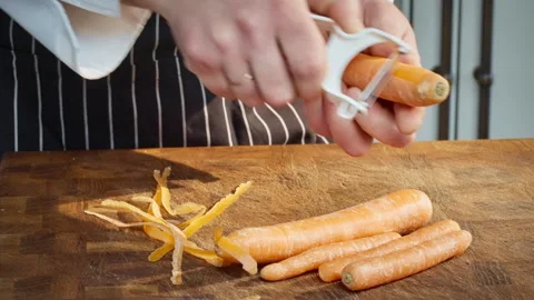 Dedicated culinary expert skillfully strips orange carrots Video stock 324575066