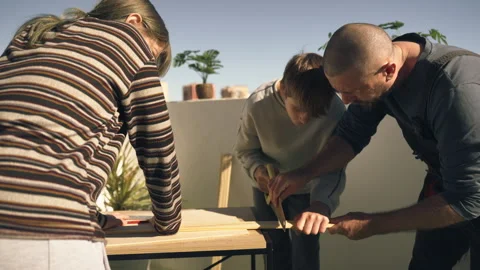 Dedicated father teaching  son how to use hand saw to cut wooden plank duri.. Stock Footage 336025460