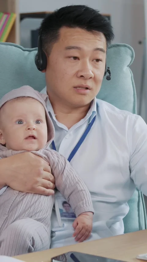A dedicated father is working from home while caring for his baby, striking a Stock Footage 314359471