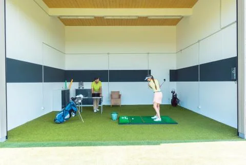 Dedicated golf coach using modern equipment while teaching a young woman 스톡 사진