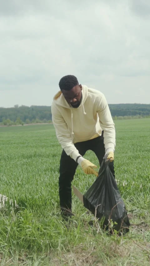 A dedicated man collects litter in a field to support valuable community Vídeo Stock 314157253