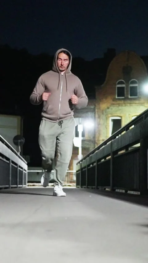 A dedicated nighttime jogger makes their way across an urban bridge during the Stock Footage 309053588