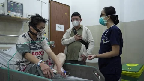 Dedicated Nurse Talks to Patient on Ventilator in Hospital Setting Stock Footage 329568979